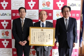 上杉一正氏が表彰状を持ち、井村砂川年金事務所長と市長とで記念撮影をしている様子