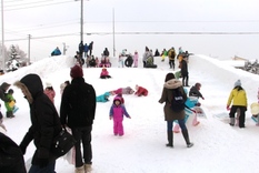 たくさんの子どもたちが雪山すべり台で遊んでいる様子