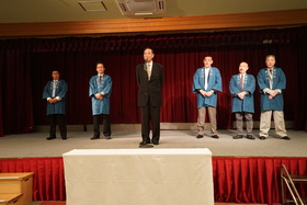 緑粋平尾会長と役員5人の皆さんがステージに上がり、平尾会長が中心であいさつしている様子