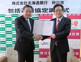 調印式で北海道銀行山本副頭取と砂川市長が協定書を持ち握手しているところ